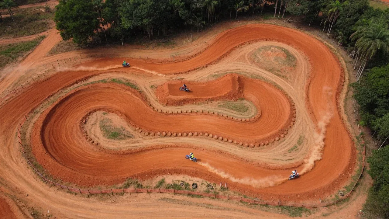 Pista sinuosa de motocross em terra batida vista do alto com relevo esculpido e vegetação lateral