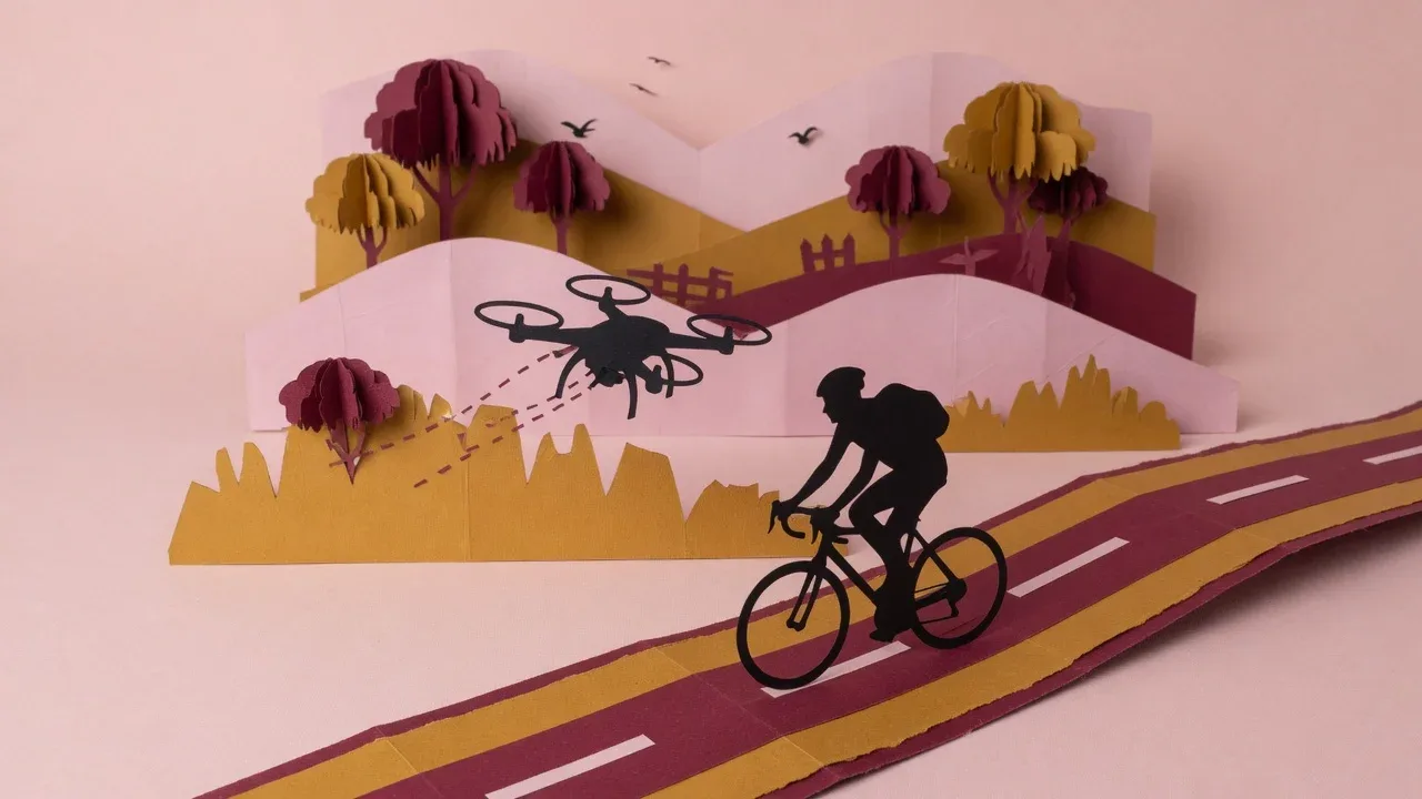 Drone acompanhando ciclista em estrada esculpido em papel artesanal