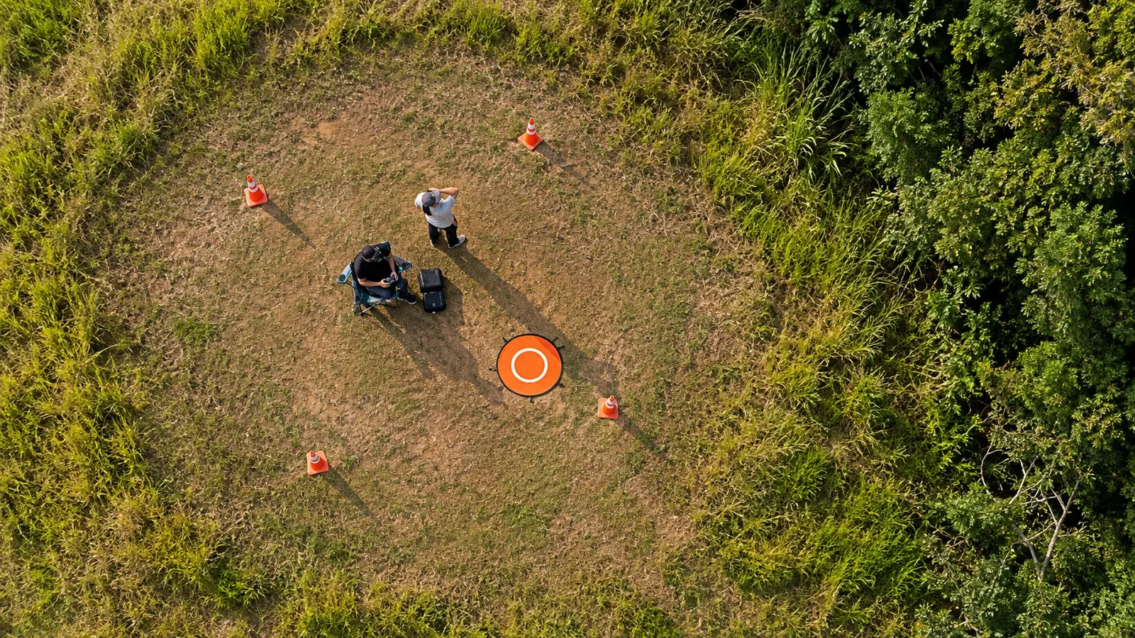 Vista aérea zenital de área de operação com padrão geométrico de solo e aeronave em voo